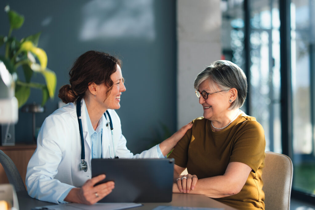 Doctor using a laptop consulting patient in bright clinic office