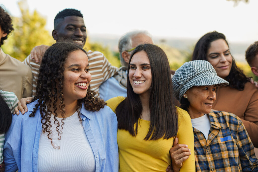 Crowd of multi generational people having fun together and hugging each other outdoors