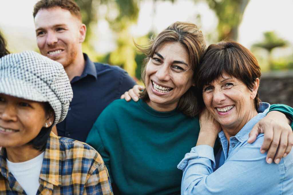 Focus on two women within a larger group hugging each other and smiling
